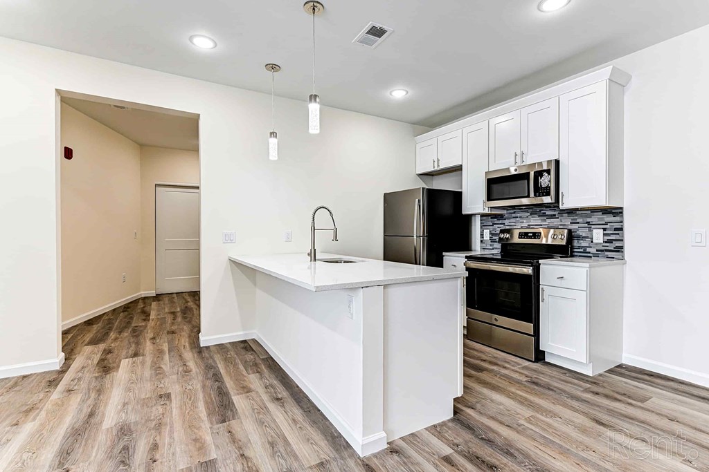 A kitchen with white cabinets and a wooden floor.