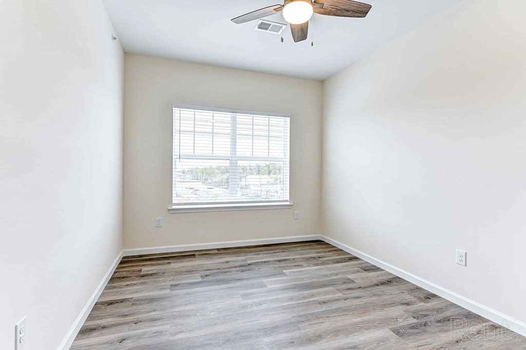A room with a ceiling fan and a window with blinds.