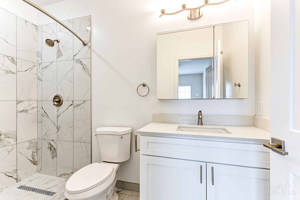 A white bathroom with a marble tile shower.