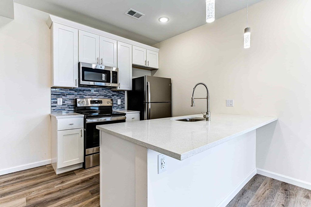 A kitchen with white cabinets and a black refrigerator.