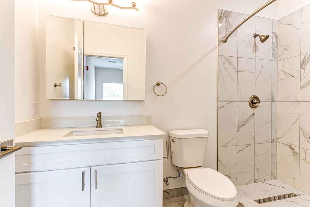 A white bathroom with a marble tile shower.