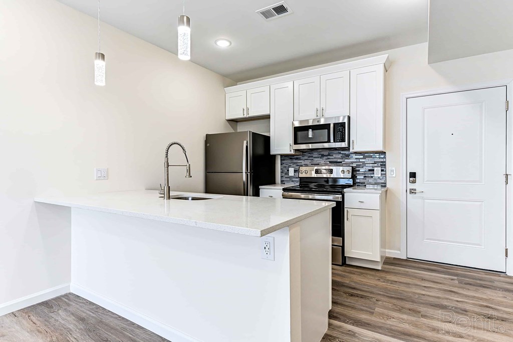 A kitchen with white cabinets and a black fridge.