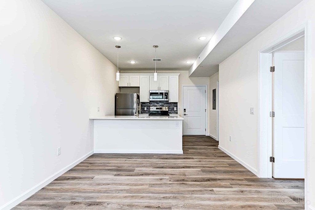 A kitchen with white cabinets and a wooden floor.