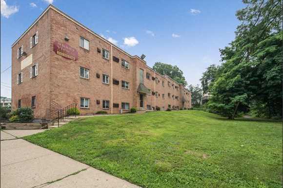 a brick building with a green lawn and a sidewalk