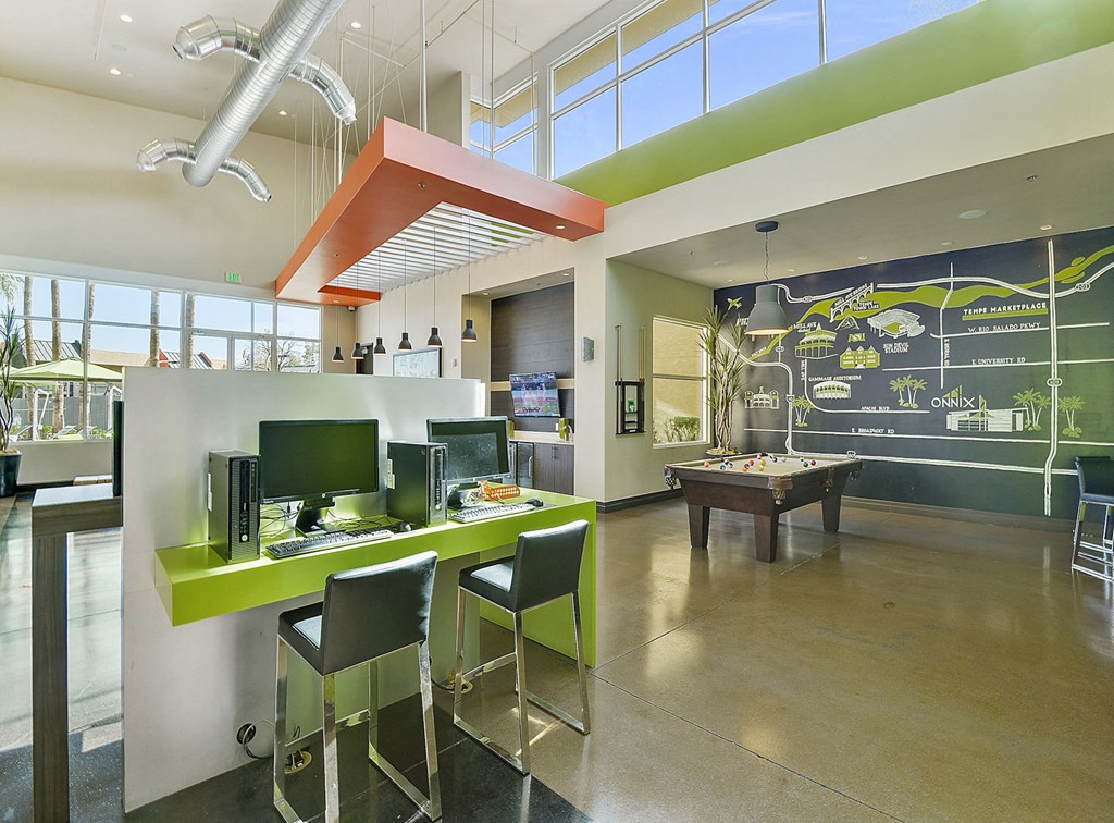 Large community room with pool table, flatscreen tv, and computers for residents of Onnix Apartments