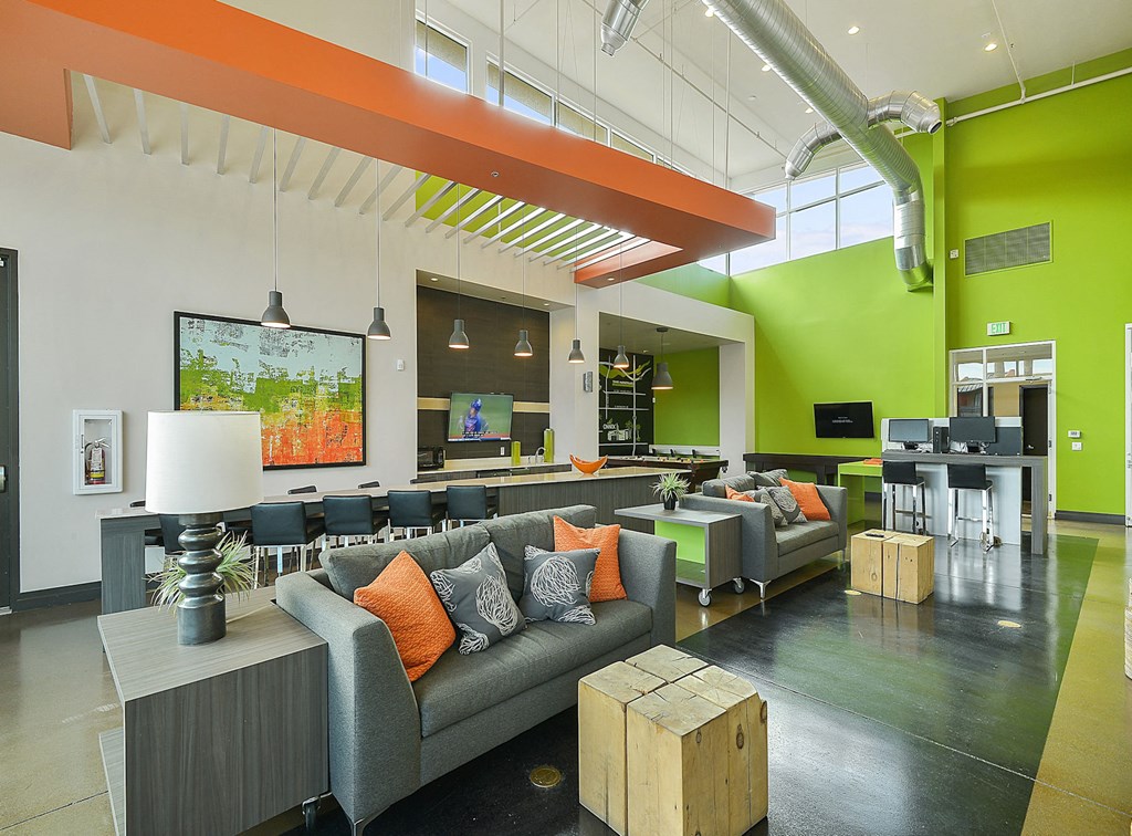 Large, open community entertaiment room with computers, tvs, and couches at Onnix Apartments in Tempe, AZ