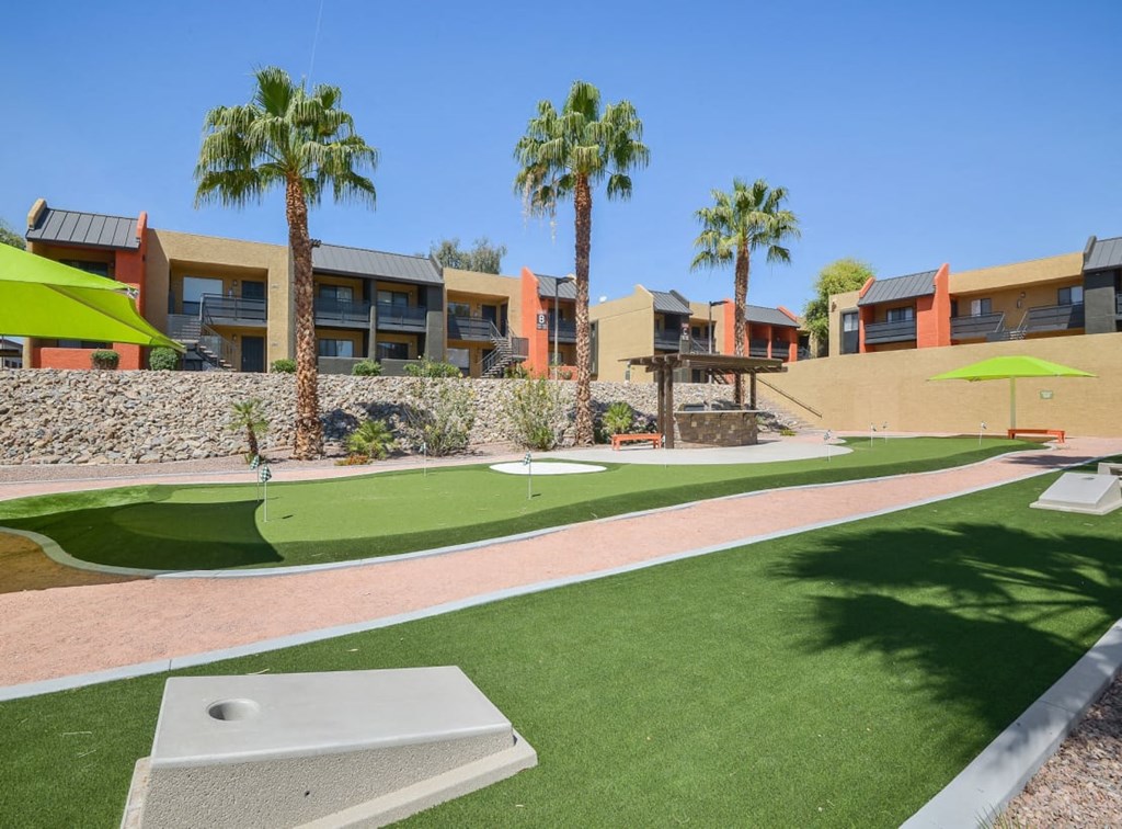 a golf course in front of a building with palm trees
