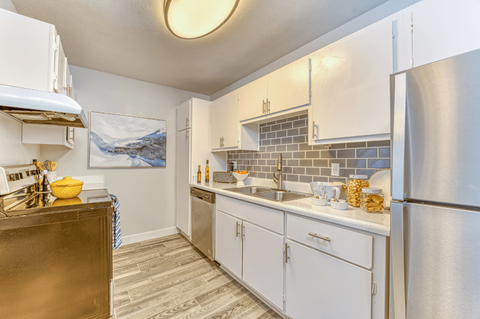 a kitchen with white cabinets and a stainless steel refrigerator