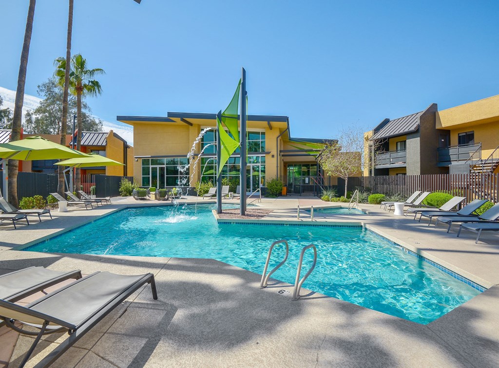 Refreshing resort-style swimming pool surrounded by lounging chairs with umbrellas