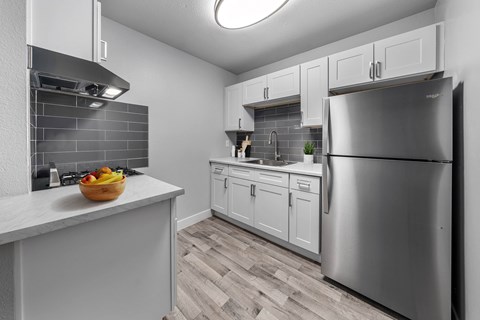 A kitchen with a refrigerator, sink, and cabinets.