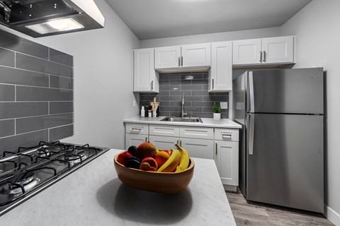 A modern kitchen with a bowl of fruit on the counter.