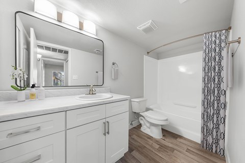 A white bathroom with a sink, toilet, and a shower.
