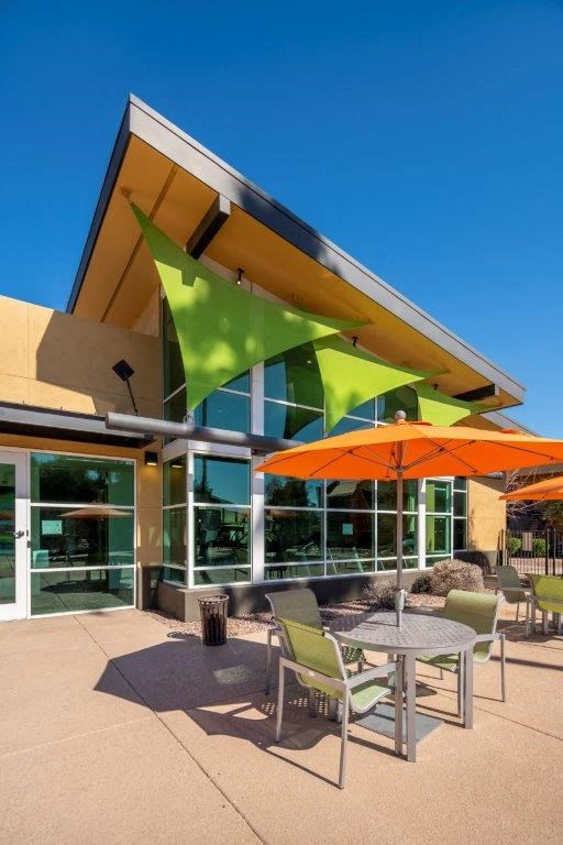 Tables with chairs and umbrellas outside of Onnix Apartments in Tempe, AZ