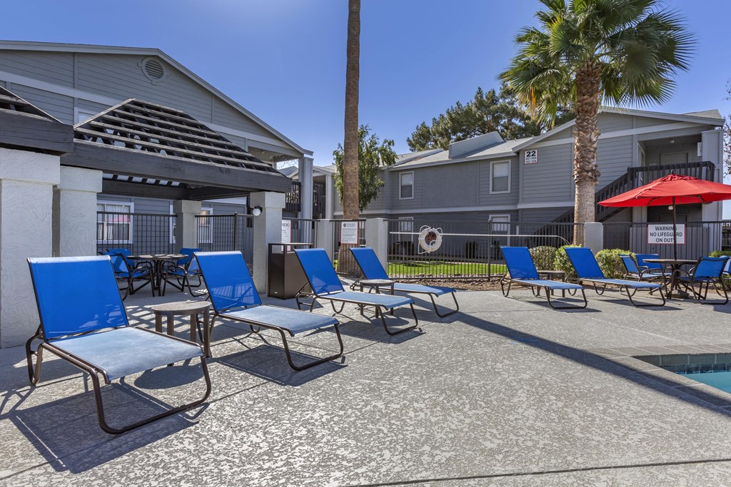 a group of lounge chairs and umbrellas near a pool