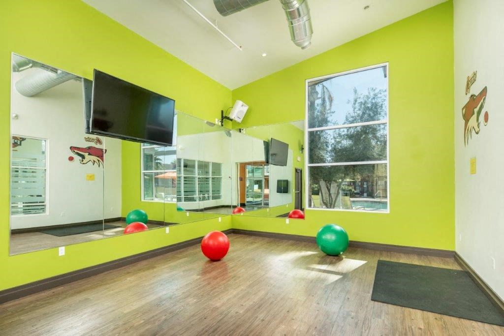 Fitness room with hardwood floors, large mirrors, and exercise equipment at Onnix Apartments