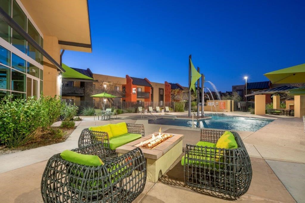 Lounging chairs by outdoor fire in front of resort-style pool at Tempe, AZ apartments