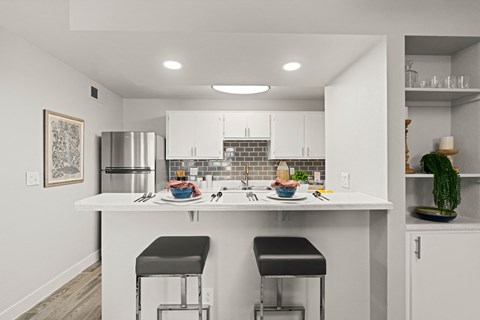 a kitchen with white cabinets and a counter top with two stools