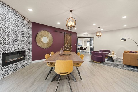 a dining area with a wooden table and yellow chairs and a purple accent wall with a fireplace