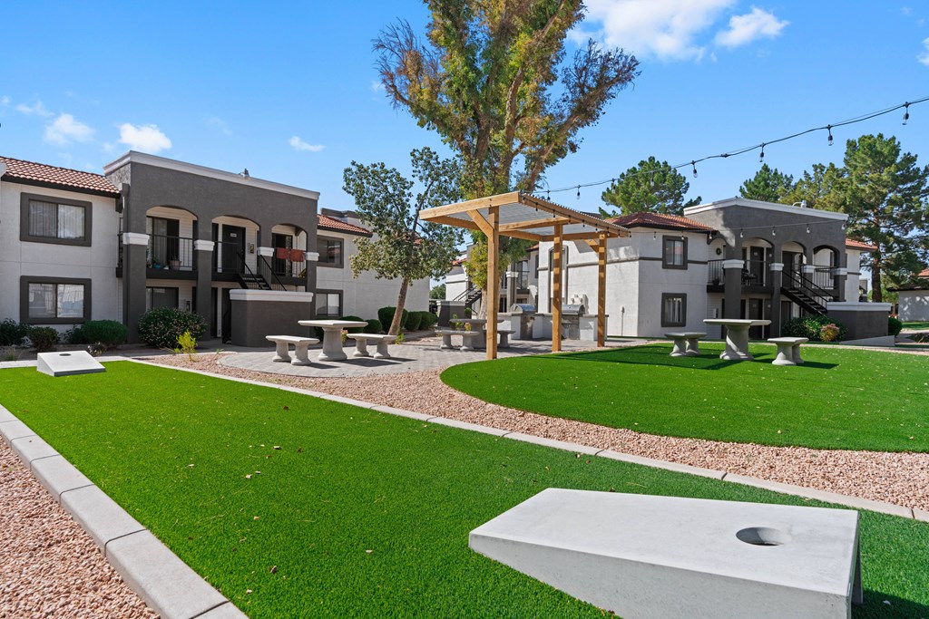 a grassy area with benches and a pergola at the whispering winds apartments in pear