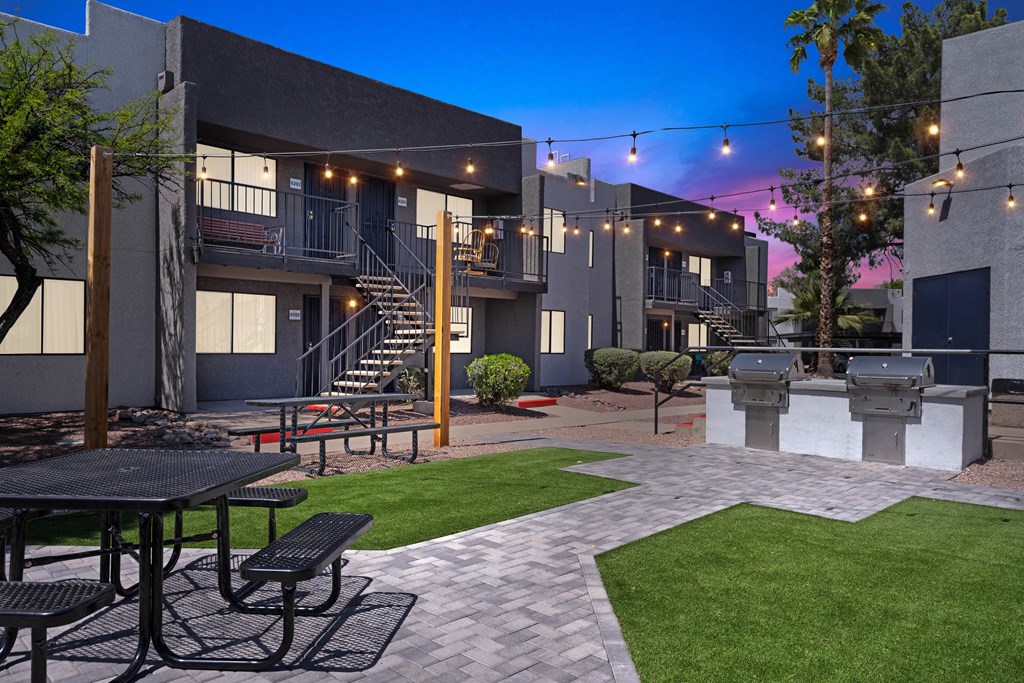a courtyard with tables and chairs and a grill at the enclave at woodbridge apartments in sugar
