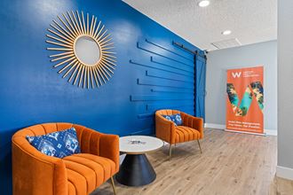 a room with two orange couches and a coffee table in front of a blue wall with - Photo Gallery