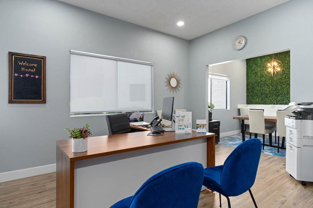 an office with blue chairs and a desk with a computer on it