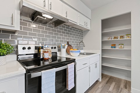 a kitchen with white cabinets and a stove and a sink