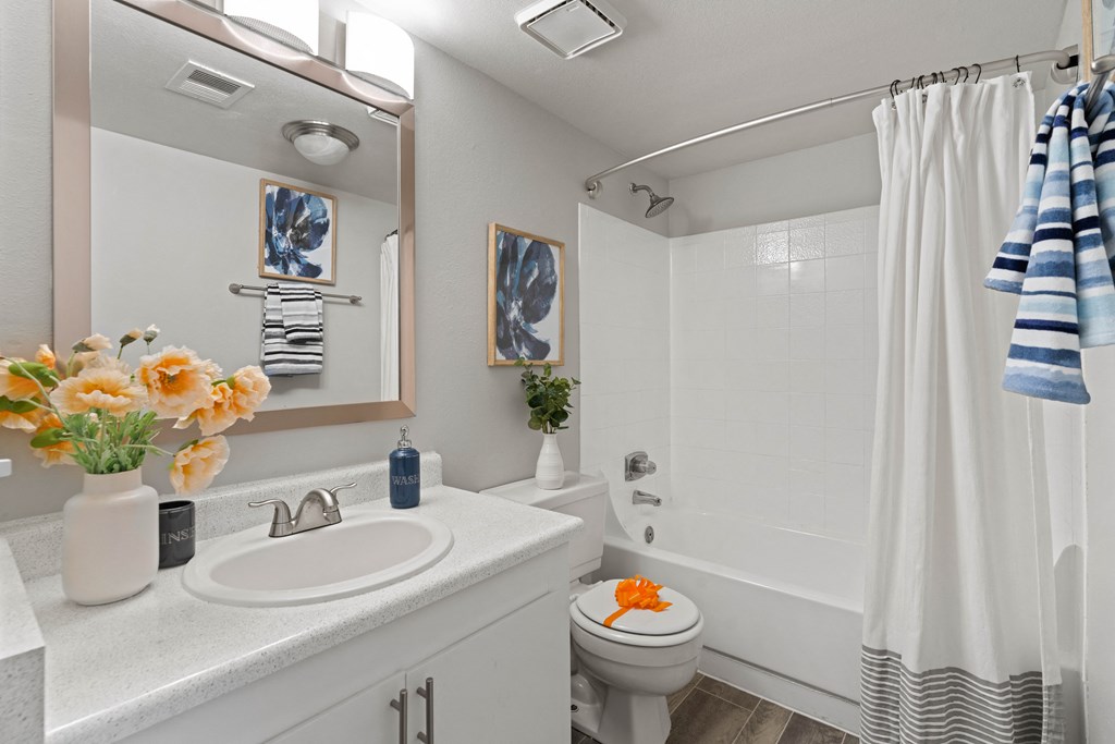 a bathroom with a white shower curtain and a white toilet next to a white sink with a