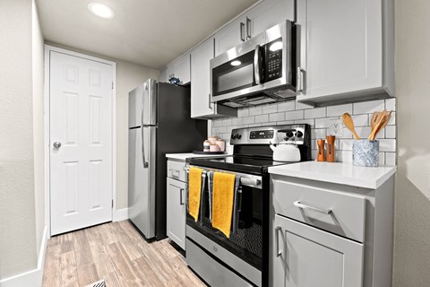 the kitchen of a studio apartment with stainless steel appliances and white cabinets