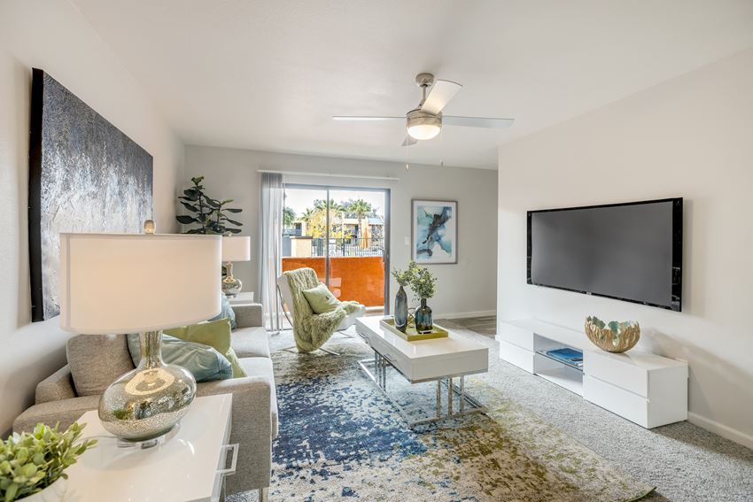 Large, newly renovated living area with carpet, and sliding doors that lead out to a balcony - Photo Gallery