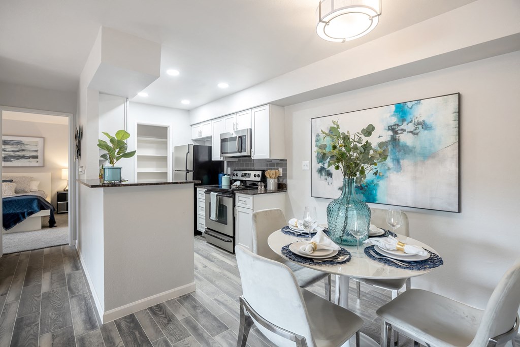Small dining area shown next to kitchen and hallway leading to bedroom with new hardwood floors 