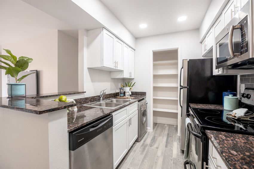Beautifully renovated galley kitchen with stainless steel appliances, white cabinets, and hardwood flooring - Photo Gallery