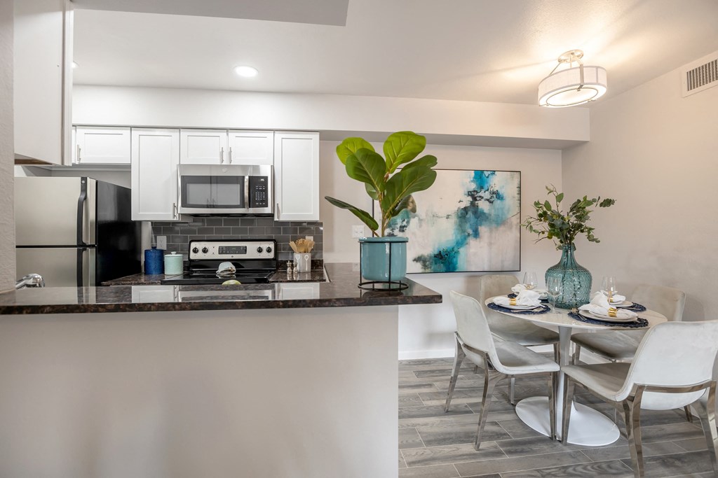 Newly renovated large dining area and kitchen with white cabinets, stainless steel appliances, and breakfast bar