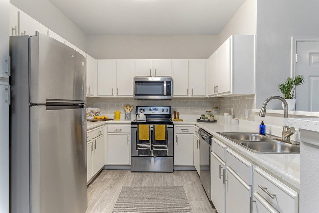 a modern kitchen with stainless steel appliances and white cabinets