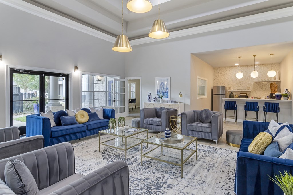 a living room with blue couches and chairs and a glass coffee table