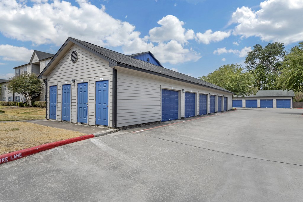 an empty parking lot in front of a building with blue doors