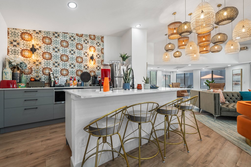 a kitchen with a white counter top with three stools in front of it and a living
