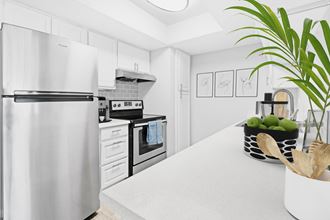 a white kitchen with stainless steel appliances and a white counter top