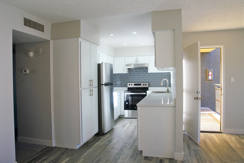 an empty kitchen with white cabinets and a stainless steel refrigerator