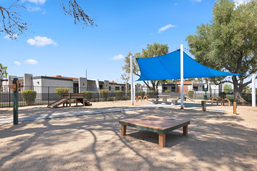 a large playground with a blue canopy and picnic tables