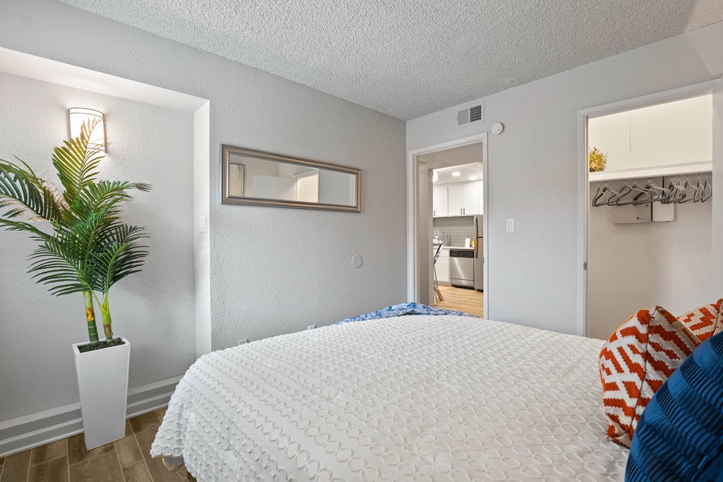 a bedroom with a large white bed and a plant in a white vase
