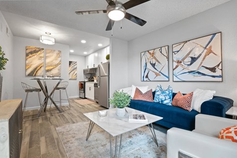 the living room and kitchen of an apartment with a blue couch