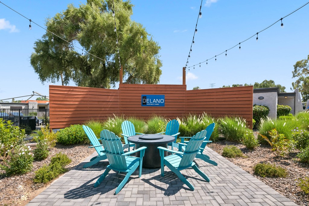 a patio with a round table and blue adirondack chairs
