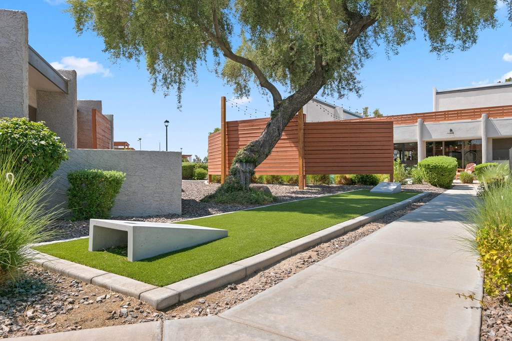 a small patch of grass in front of a building with a tree in the middle of it