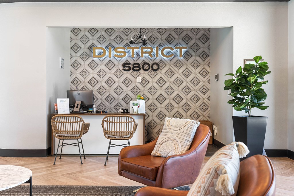 a room with a couch chairs and a desk with a computer and a sign that says district