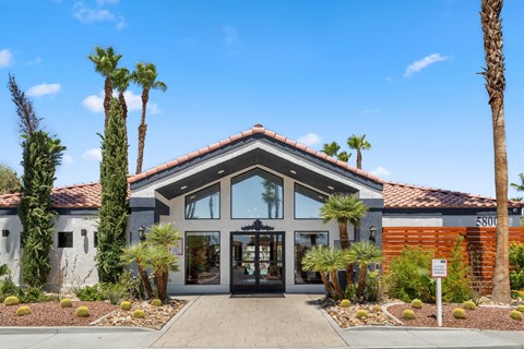 the front of a building with palm trees in front of it