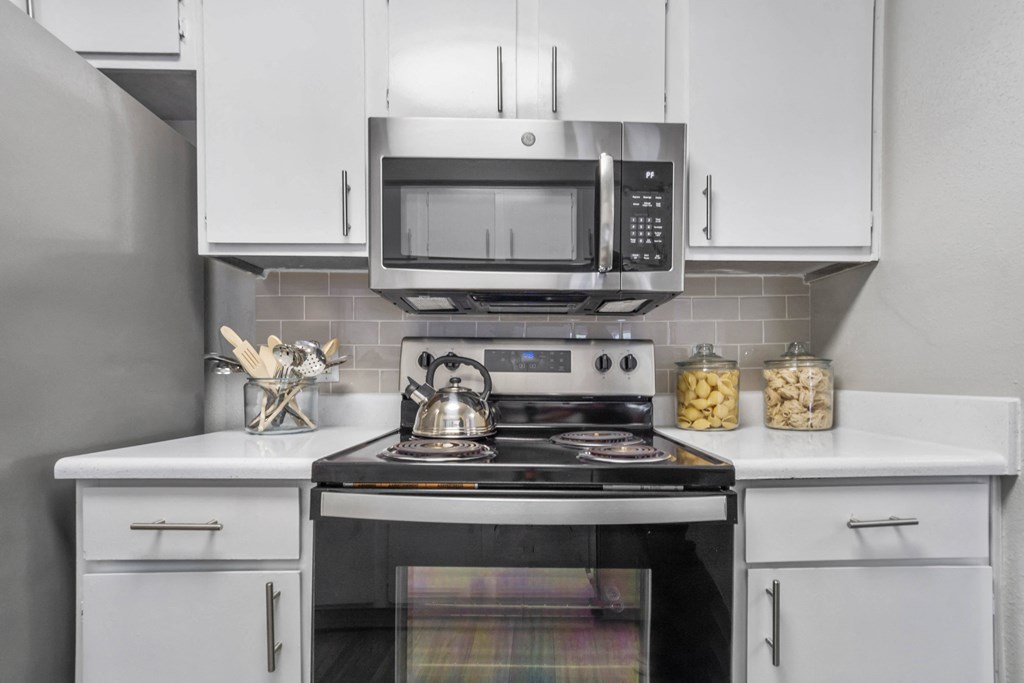 a kitchen with white cabinets and a stove and a microwave