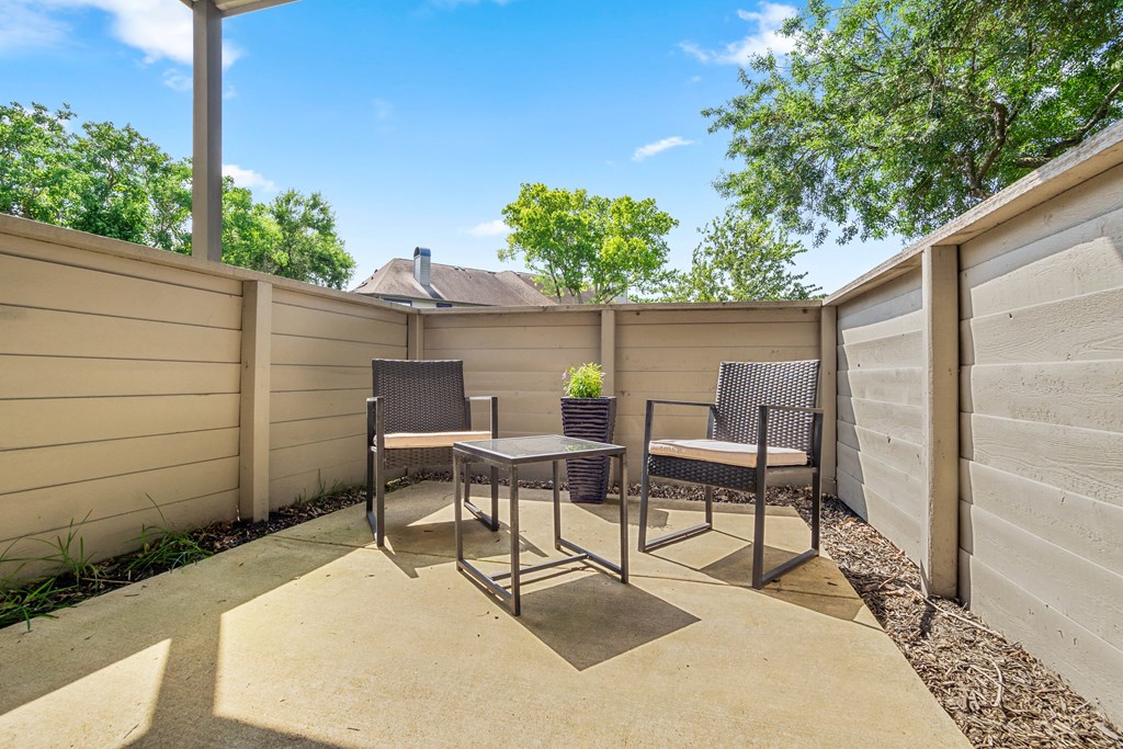 a patio with two chairs and a table in a privacy fence