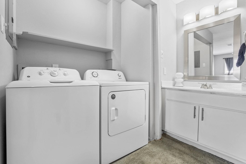 a washer and dryer in a laundry room with a sink and a mirror