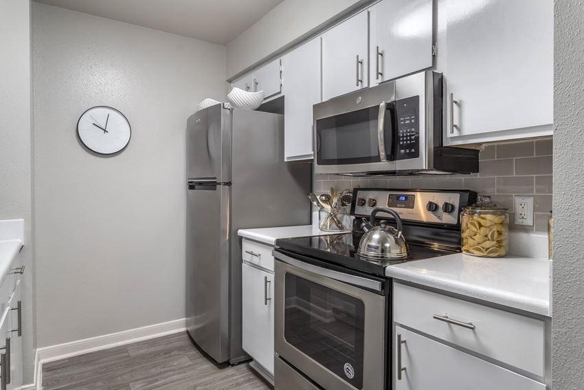 a kitchen with stainless steel appliances and a clock on the wall